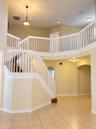 Two-story foyer featuring a vaulted ceiling, prominent staircase with a white balustrade, tile flooring, arched doorways, and a traditional pendant li