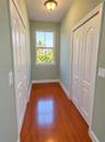 Wood-finish flooring, dual bifold closets with arched panel doors, and a double-hung window with exterior greenery