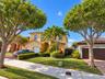 Two-story stucco exterior featuring a multi-gabled tile roof, arched entryway, and integrated two-car garage with brick-paver driveway