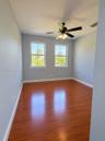 Room featuring wood-finish flooring, dual windows with grid detailing, and a multi-light ceiling fan