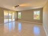 Open-concept interior featuring neutral tile flooring, multi-panel sliding glass doors, multi-pane windows, and a three-light track lighting fixture