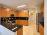 Kitchen featuring wood cabinetry, dark stone countertops, stainless steel appliances, tile flooring, and an arched doorway