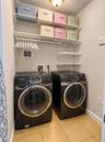 Utility area featuring metal wire shelving, tiled flooring, and dual front-loading appliances