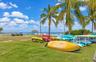 Waterfront grounds featuring mature palm trees, a thatched-roof pavilion, and direct water access