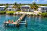 Waterfront property featuring a private wooden pier, boat lift, rock-lined shoreline, and elevated screened lanai