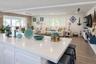 Oversized kitchen island with quartz countertop, light wood-finish flooring, stone-textured accent wall, recessed lighting, and white plantation shutt