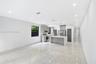 Kitchen featuring high-gloss cabinetry, stone-finish countertops, stainless steel appliances, a central island, and large-format porcelain tile floori