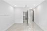 Neutral-toned porcelain tile flooring, recessed ceiling lighting, and a walk-in closet featuring built-in shelving