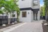 Modern two-story exterior featuring smooth stucco siding, large rectangular windows, black horizontal perimeter fencing, paver driveway, and a glass-p
