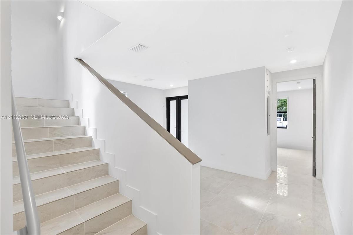 Staircase with tile-finished treads and a sleek handrail, polished tile flooring, and recessed ceiling lighting