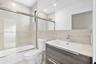 Bathroom featuring a wall-to-wall mirror, modern floating vanity with a stone-top integrated sink, floor-to-ceiling tile surround, and a glass-enclose