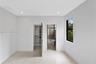 Neutral-toned tile flooring, recessed ceiling lighting, a window with a black frame, and a built-in closet featuring shelving and hanging rods