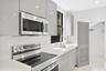 Kitchen featuring flat-panel gray cabinetry, stainless steel appliances, white solid-surface countertops, an undermount sink with a gooseneck faucet, 