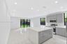 Open-concept kitchen featuring high-gloss cabinetry, a central island with a solid surface countertop, stainless steel appliances, recessed lighting, 