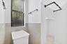 Utility space featuring a basin sink with chrome faucet, neutral wall-tile wainscoting, matte black wall-mounted hardware, and an open storage alcove