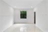 Interior space featuring large-format polished tile flooring, recessed lighting, neutral wall paint, and a single window with exterior greenery