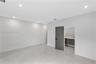 Neutral-toned large-format tile flooring, recessed ceiling lighting, and a modern slab-style interior door featuring horizontal accent grooves and mat