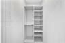 Built-in white storage system featuring dual hanging rods and adjustable open shelving