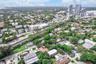 Aerial perspective featuring mature tree canopy, proximity to urban infrastructure, and coastal horizon
