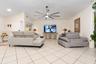 Open-concept room featuring a vaulted ceiling, large-format tile flooring, and a central multi-blade ceiling fan with integrated lighting