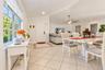 Open-concept area featuring vaulted ceilings, oversized grid-pattern windows, large-format tile flooring, and a multi-blade modern ceiling fan