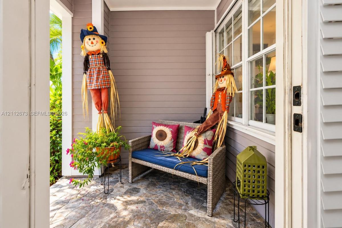 Covered entryway featuring natural stone flooring, horizontal lap siding, and multi-pane grid windows