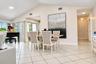 Vaulted ceilings, large-format diagonal tile flooring, and multiple sliding glass doors featuring vertical blinds
