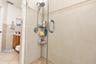 Walk-in shower featuring glass enclosure, large-format neutral wall tile, decorative tile accent band, and built-in wall niche