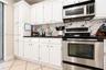 Kitchen featuring white cabinetry, dark countertops, a patterned tile backsplash, and stainless steel appliances