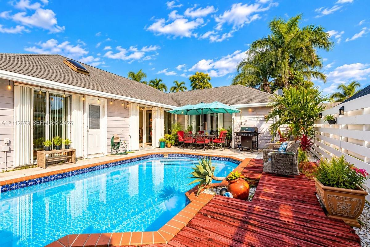 In-ground swimming pool with tile border, wood-finish decking, and privacy fencing