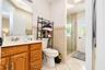 Bathroom featuring a wood-finish vanity with a molded countertop, walk-in shower with a glass enclosure, decorative tile wainscoting, and tile floorin