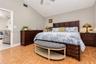 Vaulted ceiling with a central paddle fan, neutral wall paint, and wood-finish tile flooring