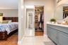 Vanity featuring a painted cabinet, solid surface countertop, and oval wall-mounted mirror, complemented by a reach-in closet with sliding mirrored do