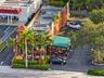 Commercial property featuring a stucco exterior, dedicated paved parking area, metal-frame outdoor canopy, and professional landscaping