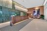Grand lobby featuring a floor-to-ceiling polished stone accent wall, custom wood reception desk with integrated lighting, expansive linear crystal cha