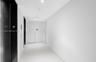Minimalist hallway featuring white tile flooring, high-contrast black elevator doors, and recessed ceiling lighting
