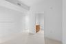 Large-format tile flooring, high ceilings, and neutral wall tones, featuring an interior doorway to a bathroom with wood-finish cabinetry and stone-lo