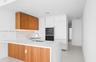 Kitchen featuring flat-panel wood-finish cabinetry, white solid surface countertops with integrated backsplash, built-in panel-ready refrigerator, sta