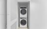 Laundry closet featuring a stacked washer and dryer set, neutral wall finish, and white louvered door