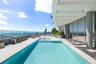 Rooftop terrace featuring an in-ground swimming pool, glass paneled perimeter fencing, expansive stone-finish decking, and a structural concrete overh