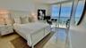 Floor-to-ceiling sliding glass doors, polished stone flooring, and expansive wrap-around balcony with coastal scenery
