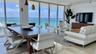 Open-concept living space featuring floor-to-ceiling glass walls, polished stone flooring, recessed track lighting, and a glass-railed balcony overloo