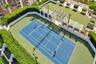 Tennis court featuring a hard surface, surrounding privacy hedges, integrated lighting, and a white architectural pergola