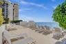 Expansive open-air terrace featuring stone-finish flooring, glass-paneled railings, and oceanfront placement