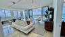 Living area featuring floor-to-ceiling glass walls, stone-finish tile flooring, and overhead track lighting