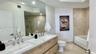 Double floating vanity with integrated rectangular sinks, polished stone-finish countertop, wood-finish cabinetry, recessed lighting, and a walk-in gl