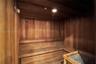 Sauna featuring natural wood paneling, multi-level slatted benches, and a dedicated heating unit