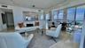 Open-concept living space featuring floor-to-ceiling windows, polished stone flooring, custom track lighting, and built-in kitchen cabinetry