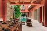 Covered courtyard featuring a swimming pool, exposed natural stone wall, timber ceiling beams, and stone flooring