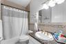 Bathroom featuring a stone-surface vanity countertop, drop-in sink with brass-toned hardware, decorative tile backsplash, and a tub-shower combination